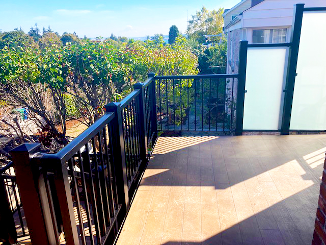 a deck with a black railing and trees