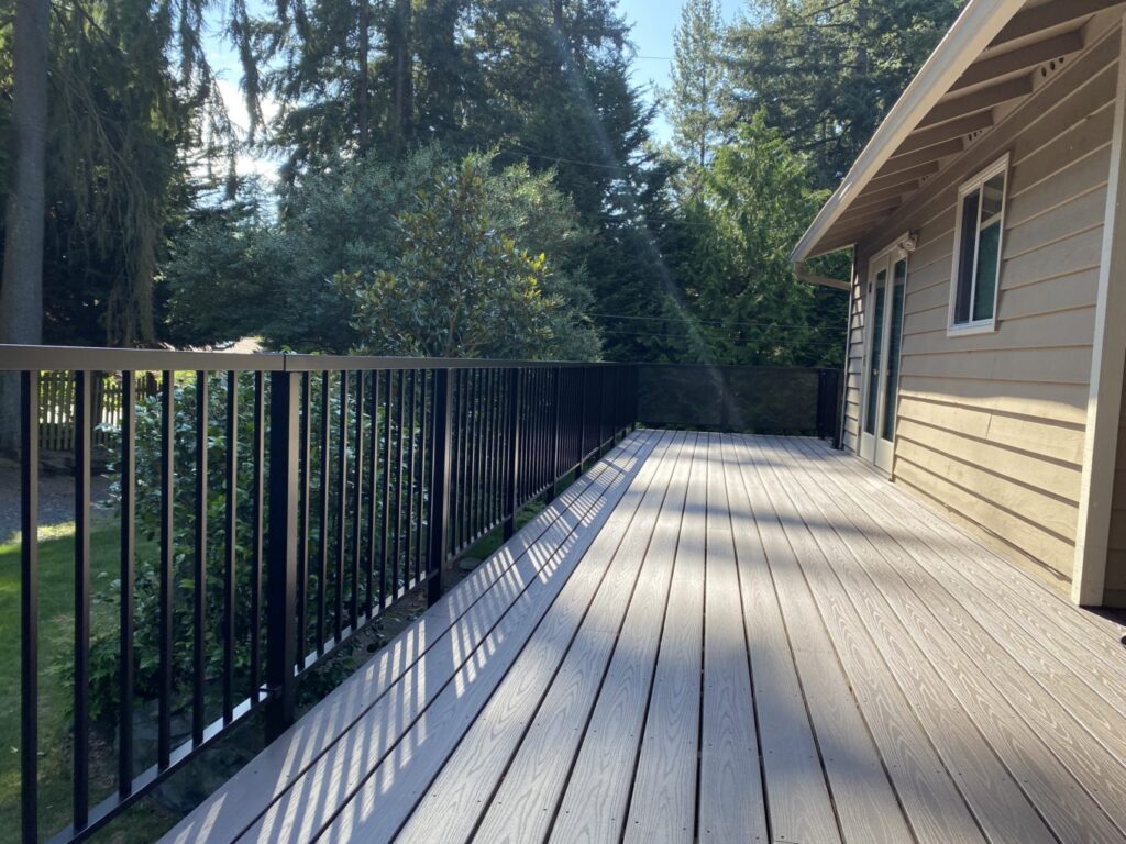 a deck with a black railing and trees in the background