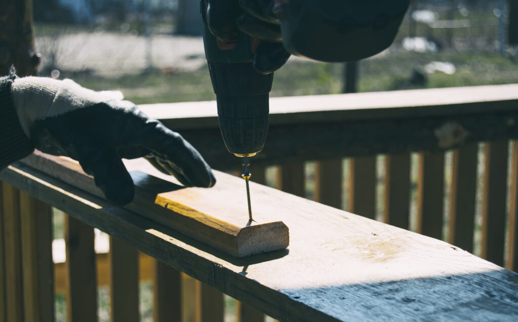 cropped hand worker drilling screw wood